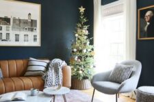 a moody living room with black walls and light and warm colored furniture, an amber leather striped sofa