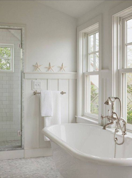 a neutral bathroom with a coastal feel, double hung windows, an oval abthtub, a shower space and neutral towels