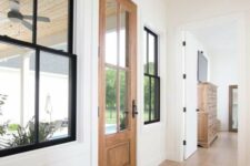 a neutral farmhouse entryway with a stained door, black double-hung windows, a printed rug is a cool space