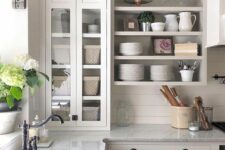 a neutral farmhouse kitchen with flat panel and open cabinets, grey stone countertops and black handles and fixtures