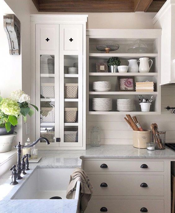 a neutral farmhouse kitchen with flat panel and open cabinets, grey stone countertops and black handles and fixtures