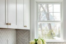 a neutral farmhouse kitchen with shaker cabinets, black countertops, a white herringbone tile backsplash and a small double-hung window