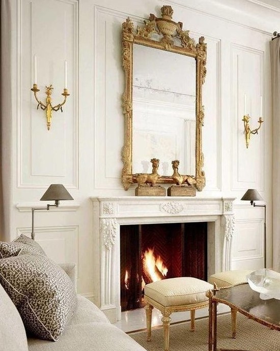 a neutral living room with a chic French fireplace that is accented with a vintage frame mirror that adds style