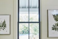 a neutral space with a black double-hung window and botanical artwork is a cool space and black frames add interest to it