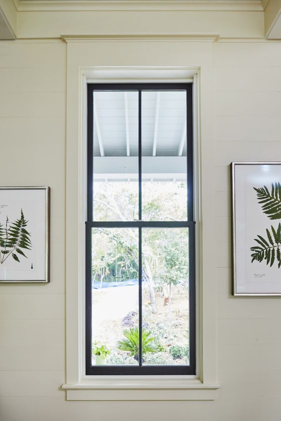 a neutral space with a black double hung window and botanical artwork is a cool space and black frames add interest to it