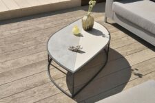 a neutral terrace with limed and gold oak decking, neutral upholstered furniture and a leaf-shaped coffee table with decor