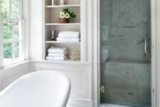 a neutral vintage-inspired bathroom with an arched niche, a tile shower space, an oval tub and a double-hung window