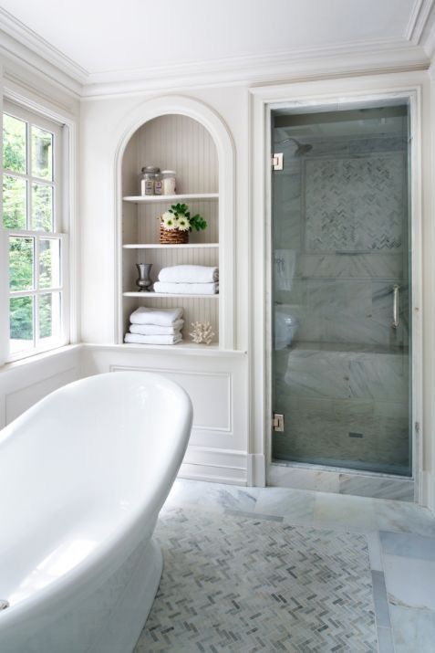 a neutral vintage inspired bathroom with an arched niche, a tile shower space, an oval tub and a double hung window