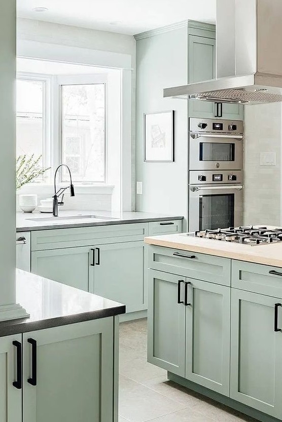 https://www.digsdigs.com/photos/2023/03/a-pale-mint-green-kitchen-with-shaker-cabinets-grey-granite-and-butcherblock-countertops-black-handles-and-stainless-steel-appliances.jpg