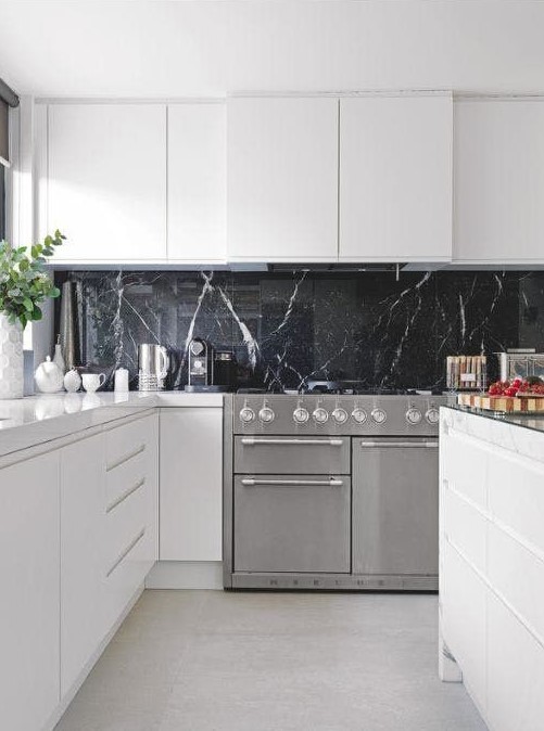 a pure white minimalist kitchen with a black soapstone backsplash that adds a refined and chic touch