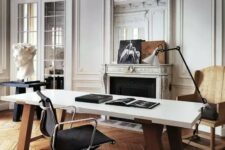 a refined and chic Parisian-inspired home office with molding, a French fireplace, a stained chair, a black table, a large desk and a cool lamp