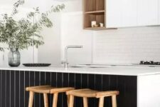 a refined contrasting kitchen with sleek white cabinets, a white subway tile backsplash, a large kitchen island with black planks, woven pendant lamps