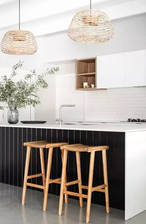 a refined contrasting kitchen with sleek white cabinets, a white subway tile backsplash, a large kitchen island with black planks, woven pendant lamps