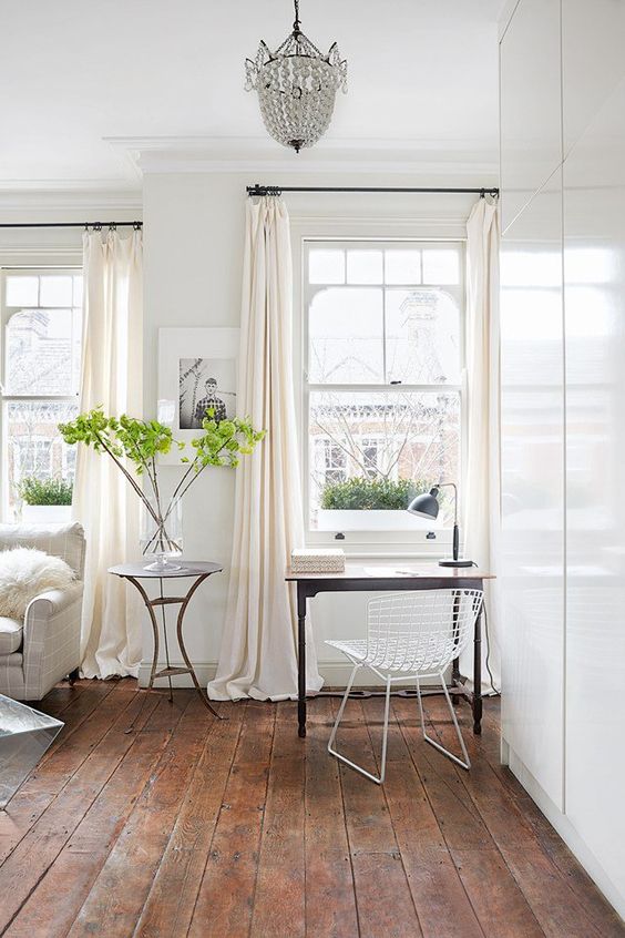 a refined light-filled space with white double-hugn windows with delicate framing, lightweight furniture and a crystal chandelier