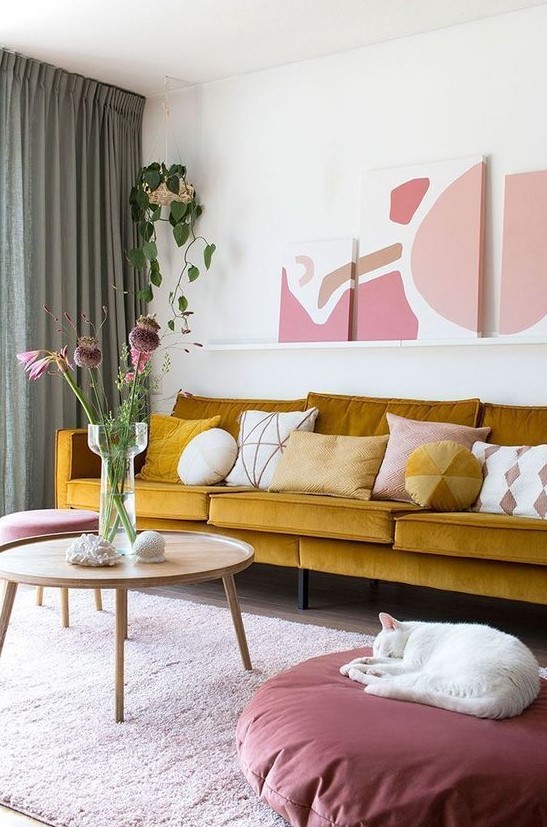 a refined living room with a mustard sofa, a ledge gallery wall, touches of pink and mauve for a very elegant and chic look