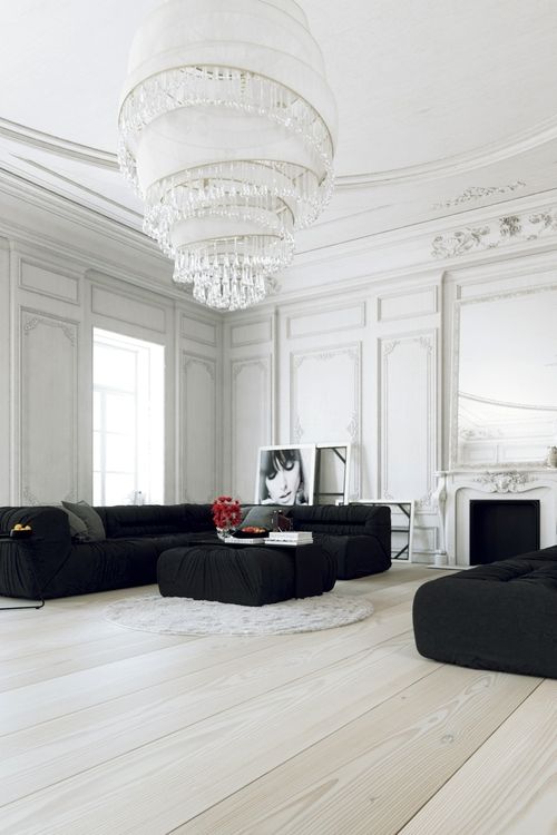 a refined white living room with molding and a vintage fireplace, a low black sectional and an ottoman plus a matching black daybed