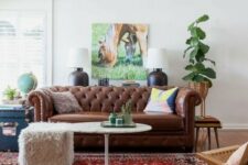 a relaxed living room with a brown leather Chesterfield sofa, a woven chair, a fur stool and some plants