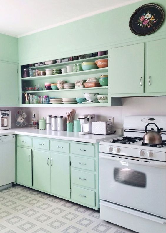 a retro kitchen with flat panel mint cabinets, a large open cabinet, a neutral backsplash and countertops and some retro decor