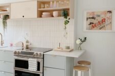 a serene kitchen with mint and open cabinets, white countertops, potted plants and tall stools