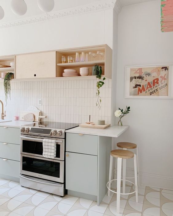 a serene kitchen with mint and open cabinets, white countertops, potted plants and tall stools