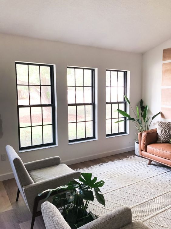 a series of black frame double-hung windows gives a lot of light and contrasts the neutral space with its black framing