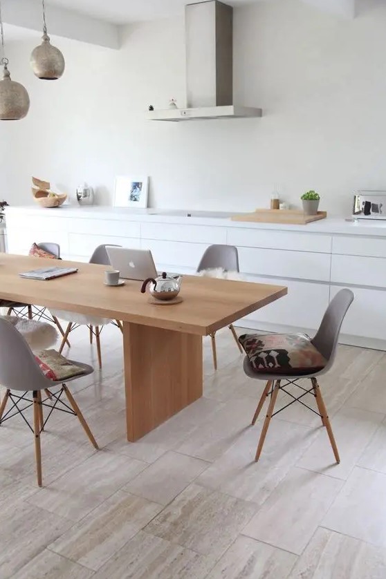 a sleek Nordic dining room with a light-stained table and grey Eames chairs plus metal pendant lamps