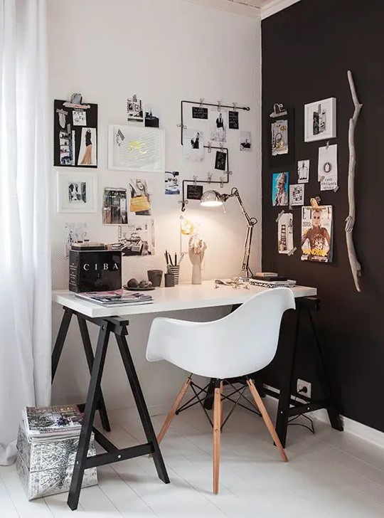 a small Scandi home office nook in black and white, with a trestle desk, a white Eames chair, a gallery wall, some lights and lamps is a lovely and cool space