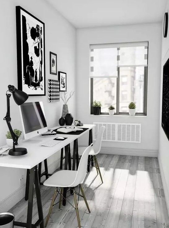 a small Scandinavian home office with a two black and white trestle desks, white Eames chairs and black and white artworks