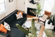 a small and cozy living room with a fireplace, a black sectional, an amber leather chair, a coffee table and a cool floor lamp