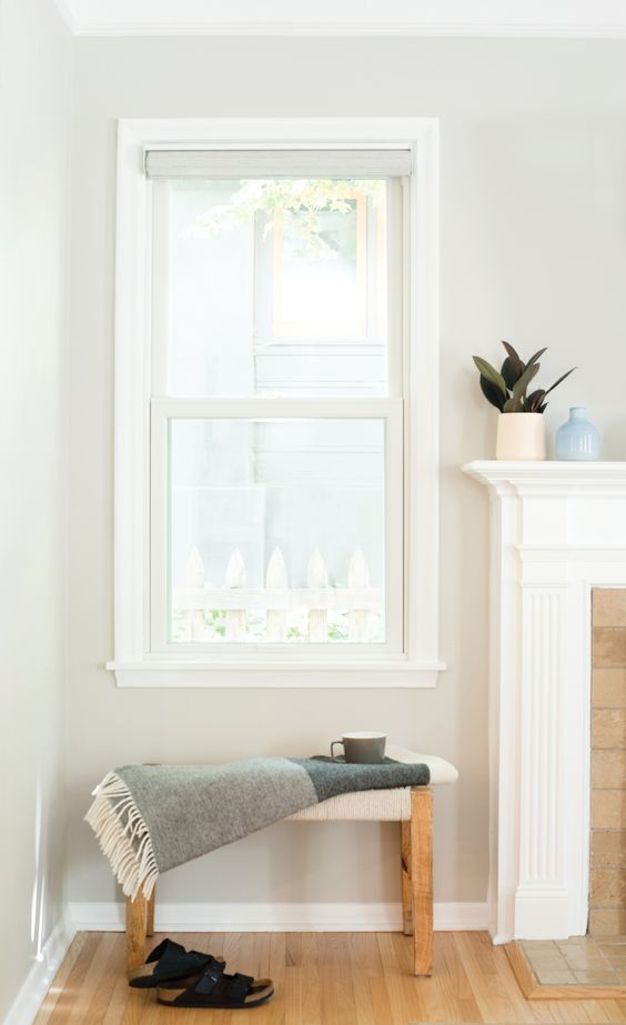 a small nook with a double-hung window, a small stool, a non-working fireplace and some lovely decor