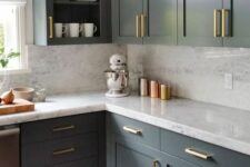 a sophisticated grey kitchen with shaker and open cabinets, white countertops and a backsplash, gold handles