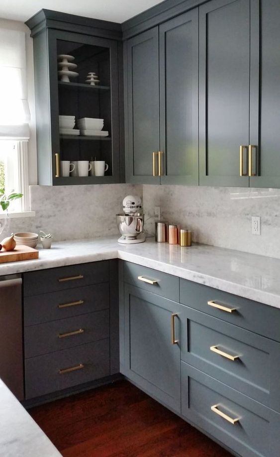 a sophisticated grey kitchen with shaker and open cabinets, white countertops and a backsplash, gold handles