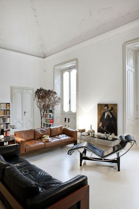 a sophisticated living room with a black and amber leather sofa, a black leather lounger, a coffee table, a statement artwork and booksehvles