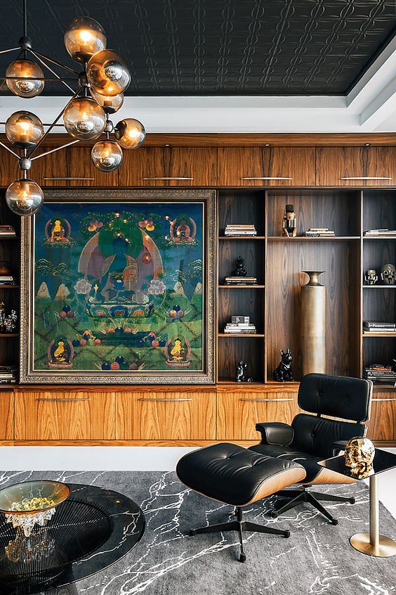 a sophisticated living room with a large stained storage unit, a large artwork, a black Eames lounger and an ottoman, a black table and a bubble chandelier