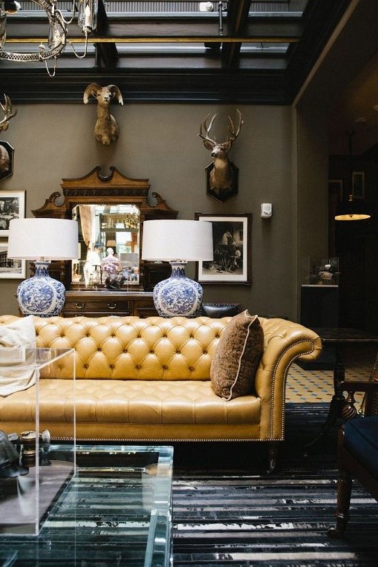 a sophisticated living room with a yellow leather Chesterfield sofa, taxidermy, plexiglass items and refined lamps