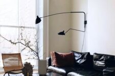 a stylish and refined living room with a black leather sofa, a red velvet ottoman and a wicker lounger