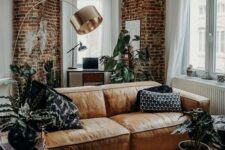 a stylish contemporary and industrial living room accented with red bricks and an amber leather couch