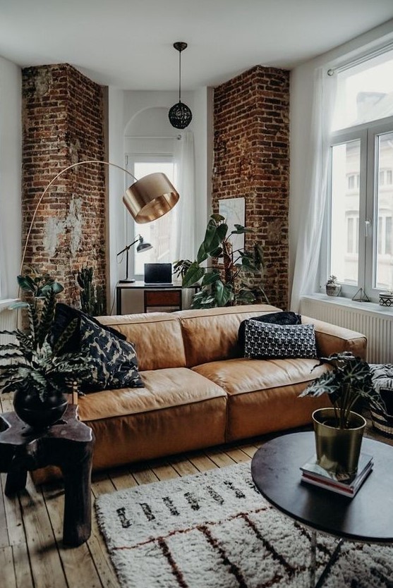 a stylish contemporary and industrial living room accented with red bricks and an amber leather couch