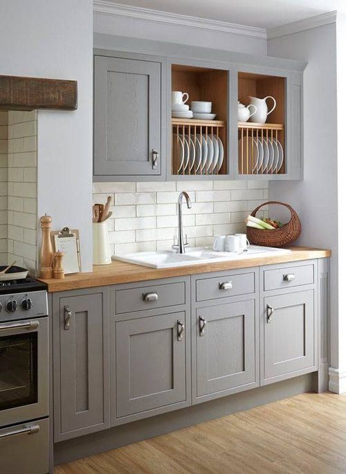 a stylish grey kitchen with shaker cabinets, open upper ones, butcherblock countertops and wooden beams is chic