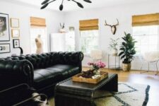 a stylish living room with a black Chesterfield sofa, a matching metal table, woven shades and a gallery wall is very chic