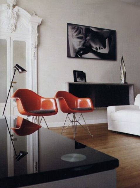 a stylish living room with a white sofa, a sleek black coffee table, a box shelf, a couple of amber Eames chairs