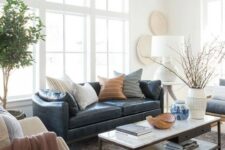 a stylish modern and boho living room with a navy leather couch accessorized with various pillows