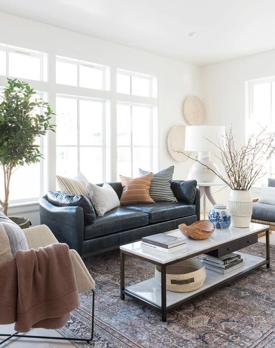 a stylish modern and boho living room with a navy leather couch accessorized with various pillows