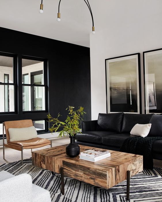 a stylish modern living room with a black leather sofa, a catchy timber coffee table, an amber chair, a printed rug