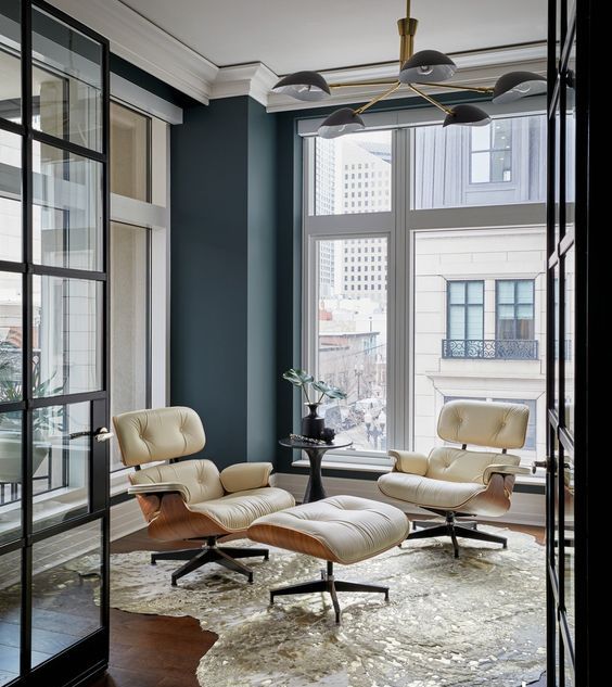 a stylish sitting zone with creamy Eames loungers and an ottoman, a gilded rug and glazed walls is like a small sunroom