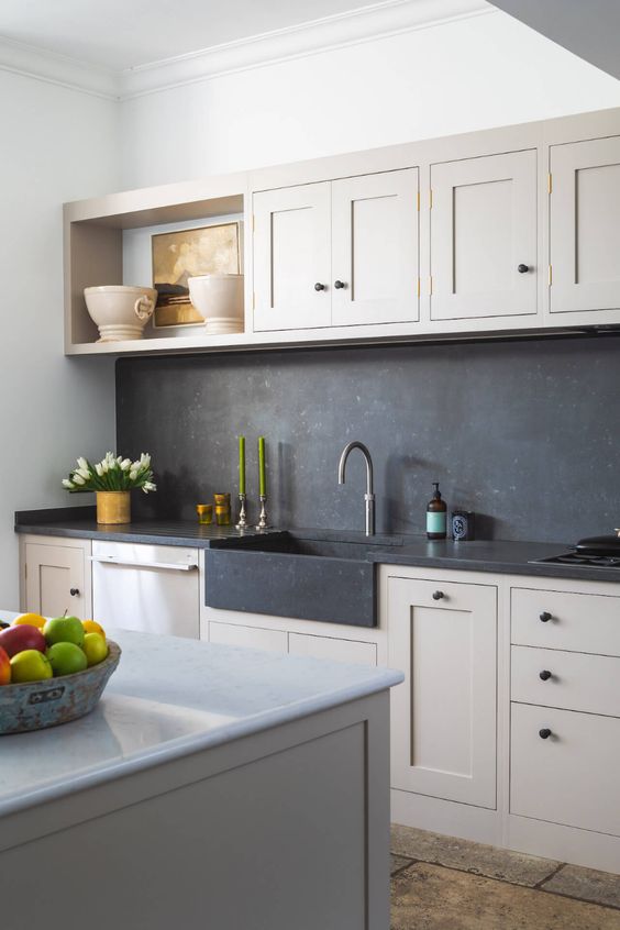 a tan kitchen with shaker cabinets, a large kitchen island, a black soapstone backsplash and countertops is a very cozy space