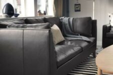 a timeless black and white space with a black leather Stockholm sofa on wooden legs looks cool