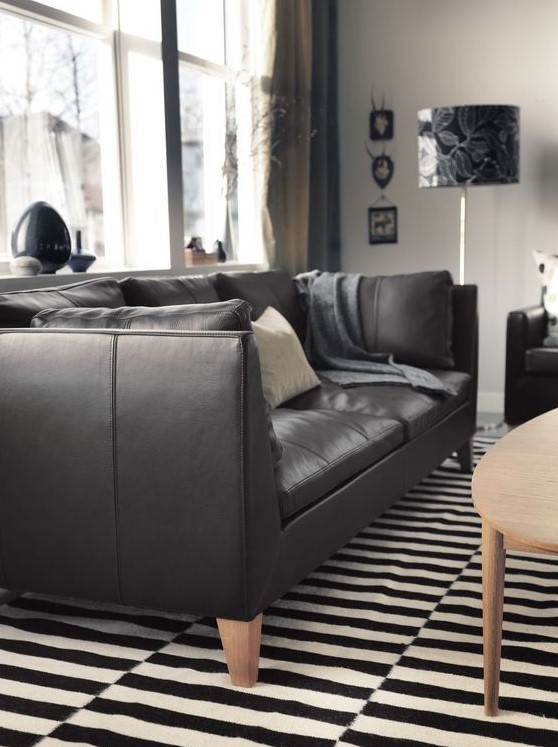 a timeless black and white space with a black leather Stockholm sofa on wooden legs looks cool