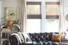 a vintage and shabby chic living room with a brown leather Chesterfield sofa, a matching white ottoman and a refined gilded chandelier