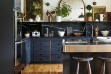 a vintage graphite grey kitchen with flat panel cabinets and a large kitchen island, black soapstone countertops and a backsplash, an open shelf and some artwork